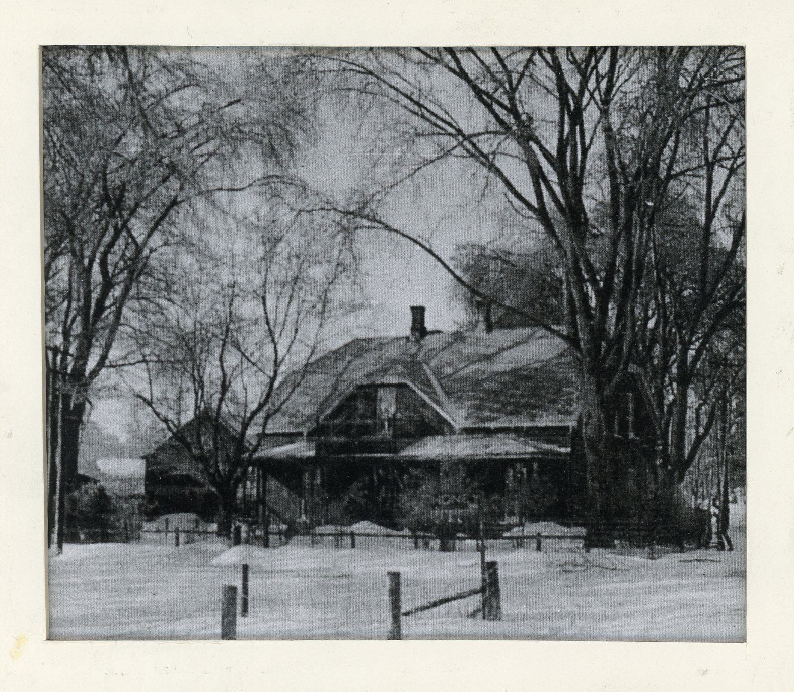 Photograph of Elmbank, Maude Abbott’s home, in winter, black and white. It is a two-storey brick house with a gable roof, two chimneys and a gallery on both floors. There is a wooden fence and a sign marked “HONEY” in front of the house, and many trees on the property.