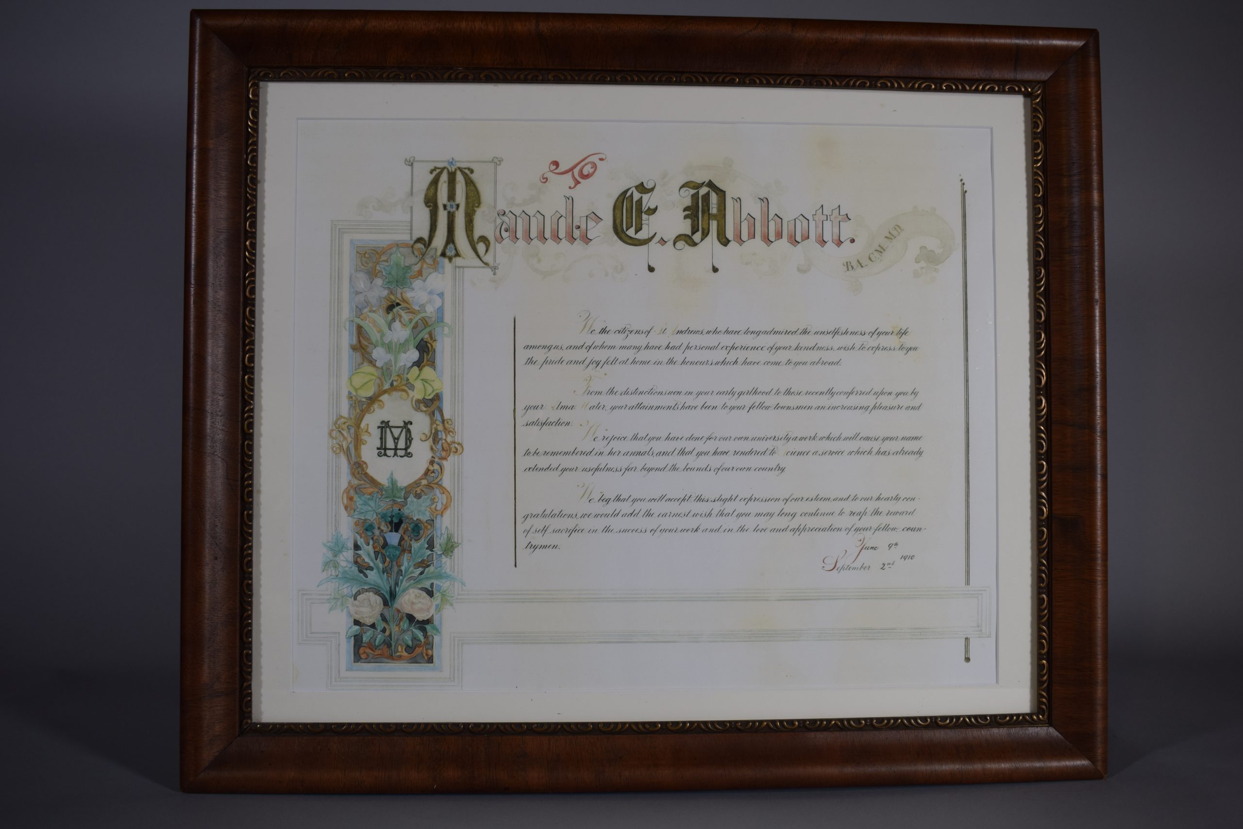Certificate of recognition; colour. At the top, “Maude E. Abbott” with raised initials and a scroll to the right with the letters “B.A., C.M., M.D.” On the left, a banner with flowers in a black frame surrounds a golden circle with the overlapping letters “MD”.
