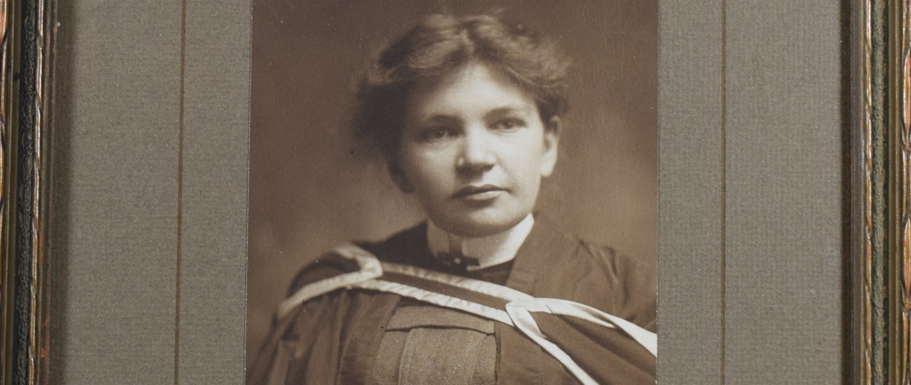 Black and white photograph of Maude Abbott as a young adult, from the waist up. She is wearing a graduation gown. Her dark hair is tied behind her head and she is looking slightly to her left. There is a signature in the lower right corner, in ink: “Sincerely Yours. Maude Elizabeth Seymour Abbott”. The printer’s signature appears below this: “Rice. Montreal”.