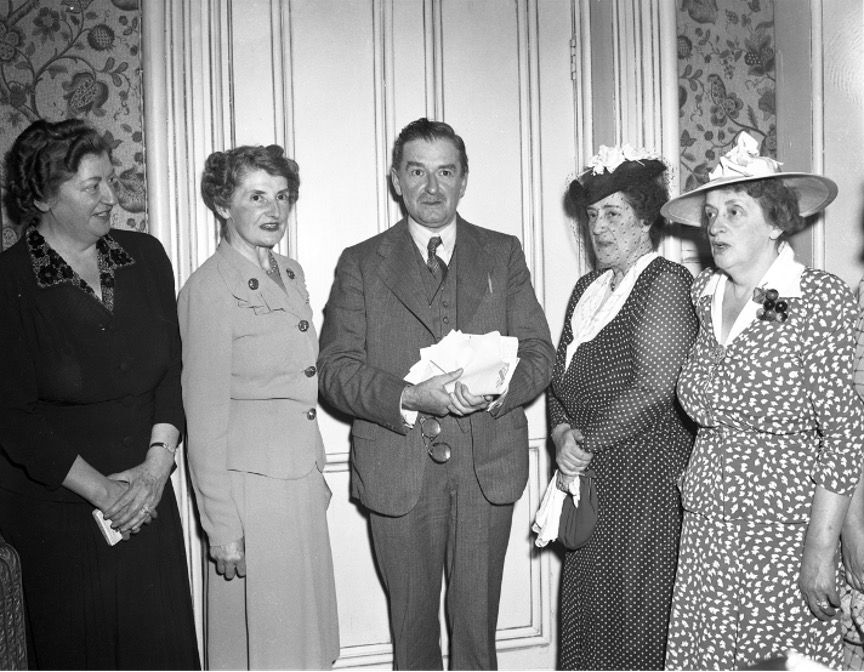 Black and white photograph showing Maurice Duplessis with some papers in his hands. Two of his sisters are standing on his left. The two others are standing on his right.