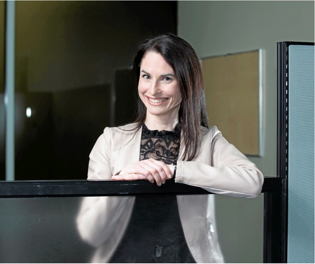 Photograph of Kim Alarie leaning on a glass partition.