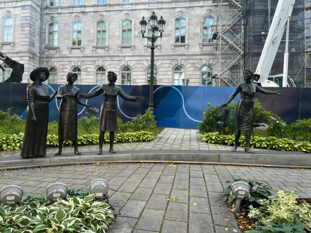 Colour photograph showing bronze statues of Marie Lacoste-Gérin-Lajoie, Idola St-Jean, Thérèse Forget-Casgrain and Marie-Claire Kirkland. Behind them, a lamppost and the stone facade of the Quebec Parliament Building are visible.