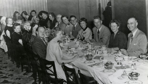 Black and white photo of people seated at a table during a banquet.
