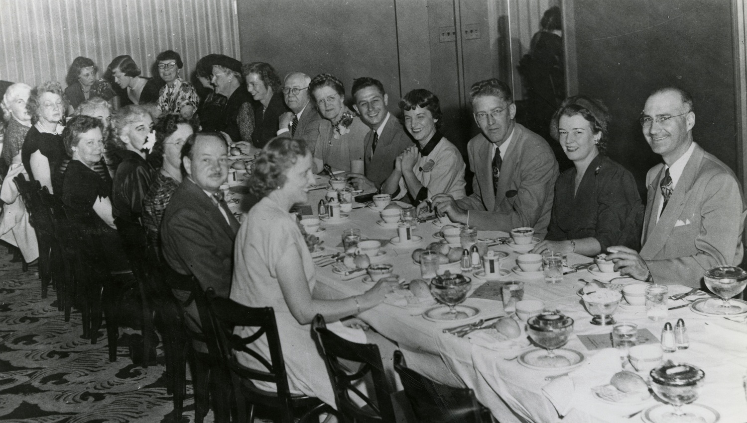 Black and white photo of people seated at a table during a banquet.
