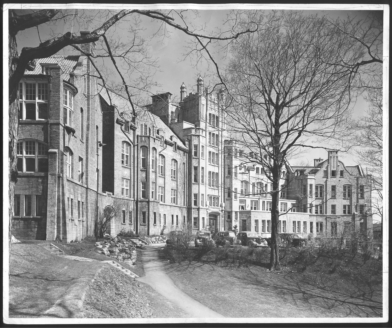 Black and white photo of an Edwardian brick building surrounded by trees.
