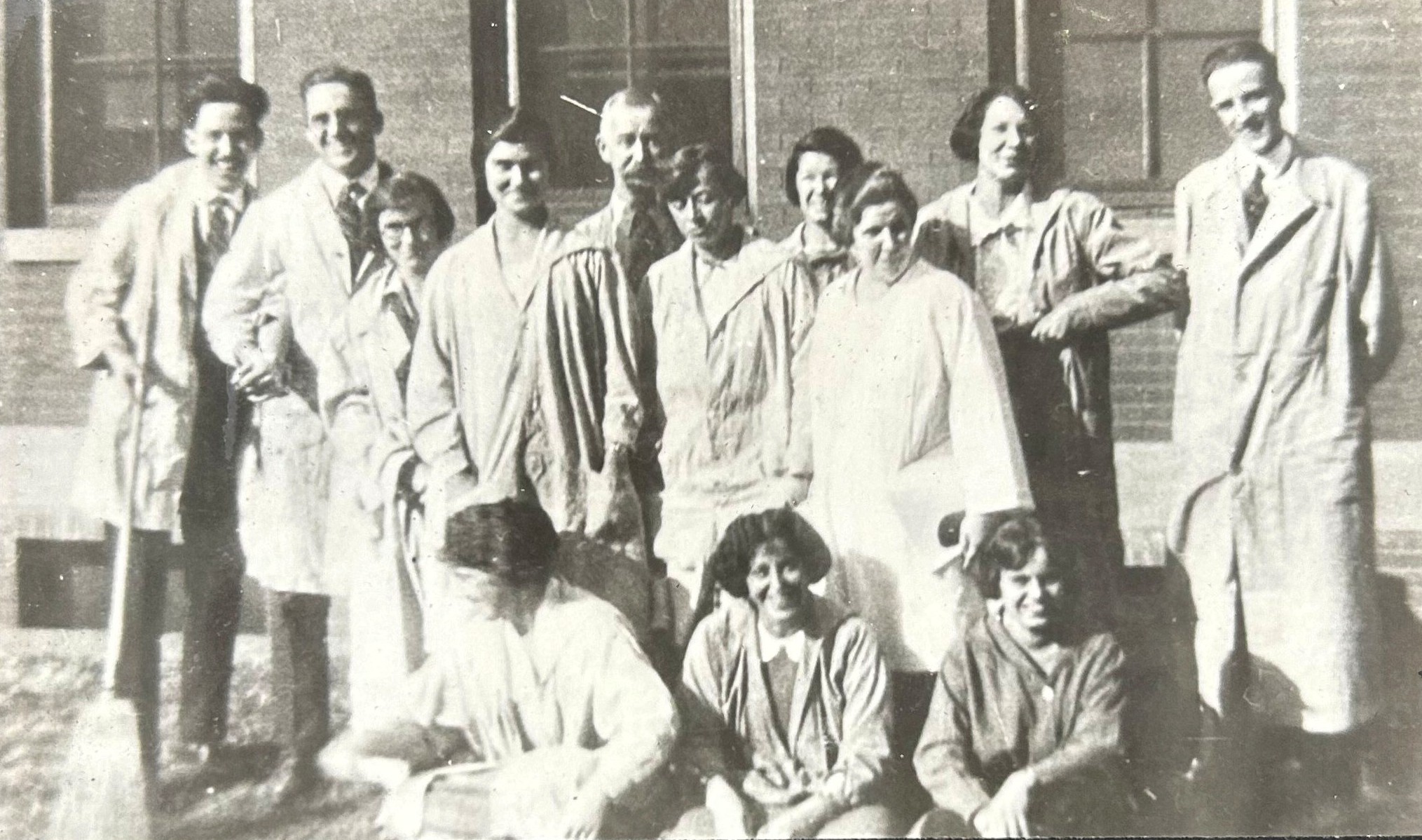 Black and white group photo of students of all genders posing in rows, wearing lab coats.