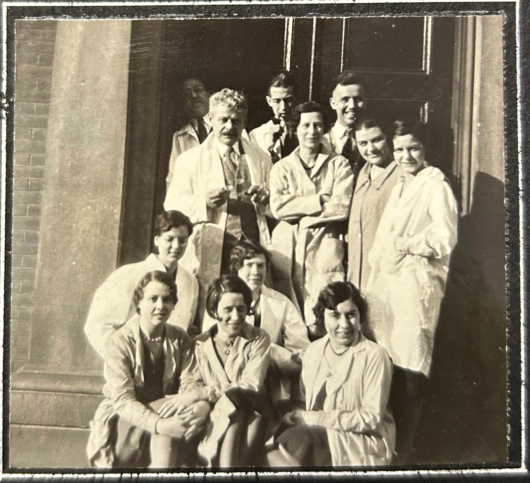 Black and white group photo of students of all genders posing in rows, wearing lab coats.