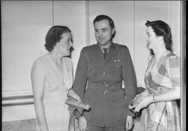 Black and white photo of three people in conversation, looking at each other.