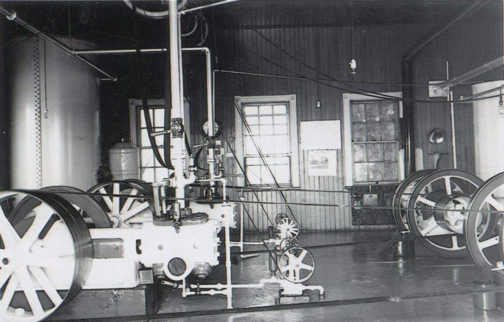 Black and white photograph inside the fog horn building at the Metis Lighthouse showing the gas-powered engines used to power the foghorn at the Metis lighthouse.