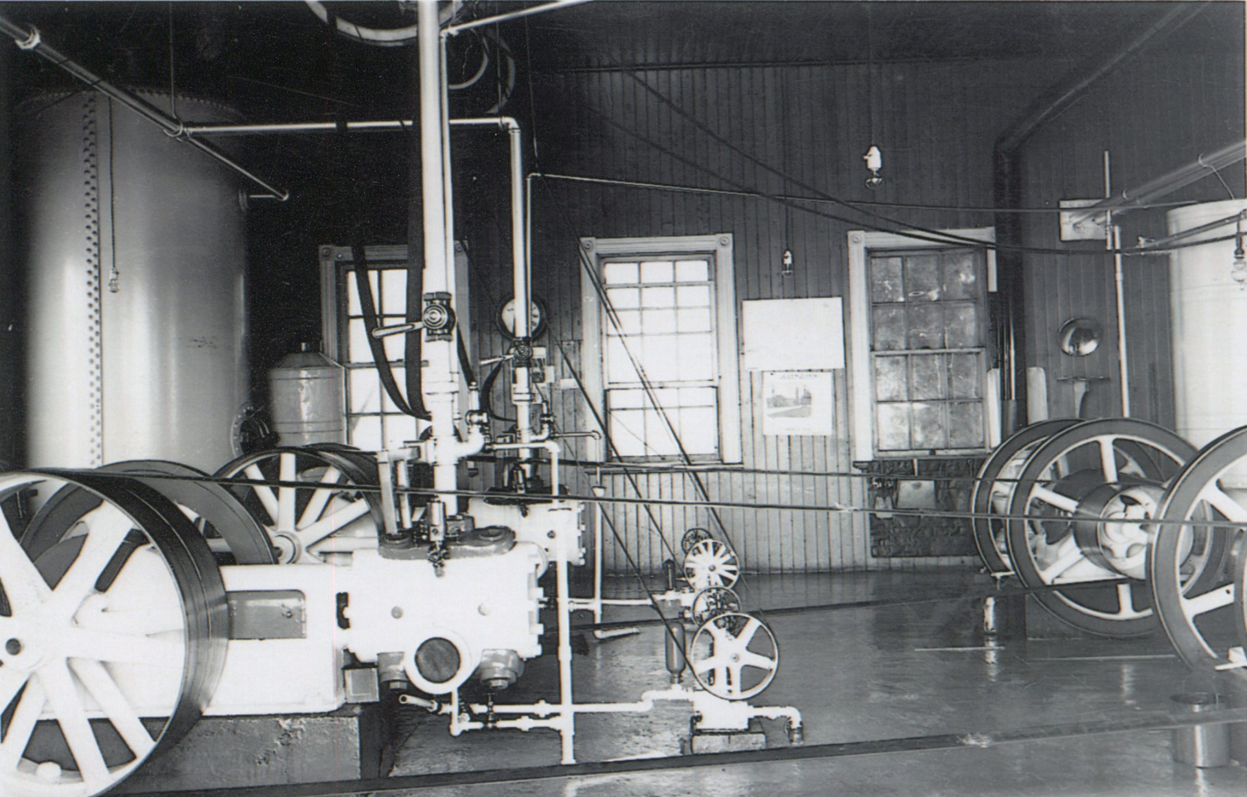 Black and white photograph inside the fog horn building at the Metis Lighthouse showing the gas-powered engines used to power the foghorn at the Metis lighthouse.