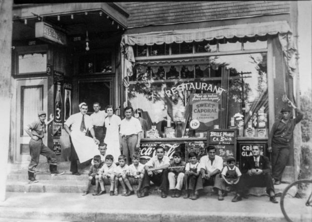 Many boys and a few men are sitting by the front window of Jeff Geoffrion’s restaurant. Standing to their left, four men and a woman seem to make up the entire staff. There is a lit marquee in front of the entrance.