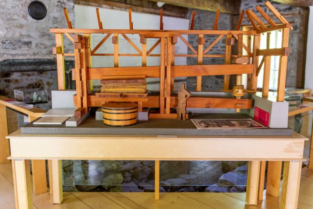 Placed on a table in the cider press house, this wooden model represents the apple press built by Didier Joubert and how it was integrated to the framework of the building at the time. The press consisted of a large lever that was progressively lowered by a human-powered screw.