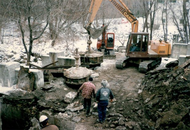 In the centre, two men are watching as the operator of a crawler excavator removes turbines from the structure on a snowy day. The basin was drained during the refurbishment of the mills’ dike in the late 1990s.
