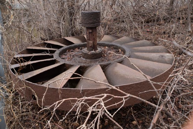 A rusted waterwheel from a hydraulic turbine was left on the ground near the miller’s house.