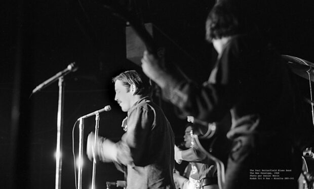 Black and white photograph of Paul Butterfield and two members of his Blues Band, as seen from the side of the stage during a concert at The New Penelope.