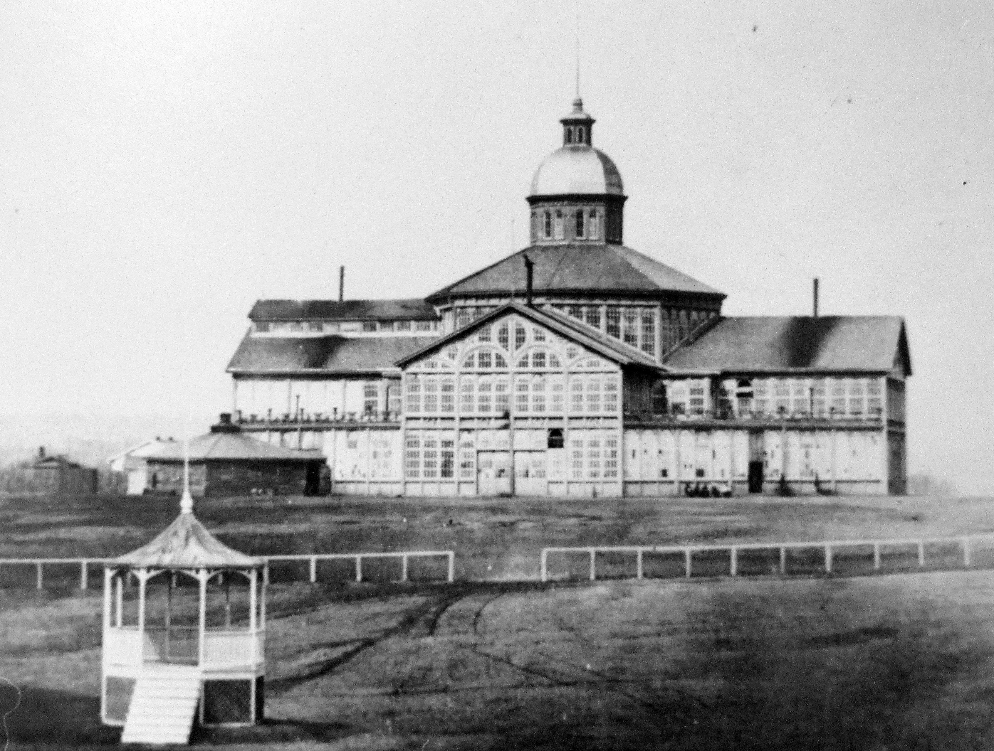 A three-storey palace with a domed tower in the centre. The palace is dominated by dozens of glass windows that cover most of the walls all the way around. The building is surrounded by grass and park land.