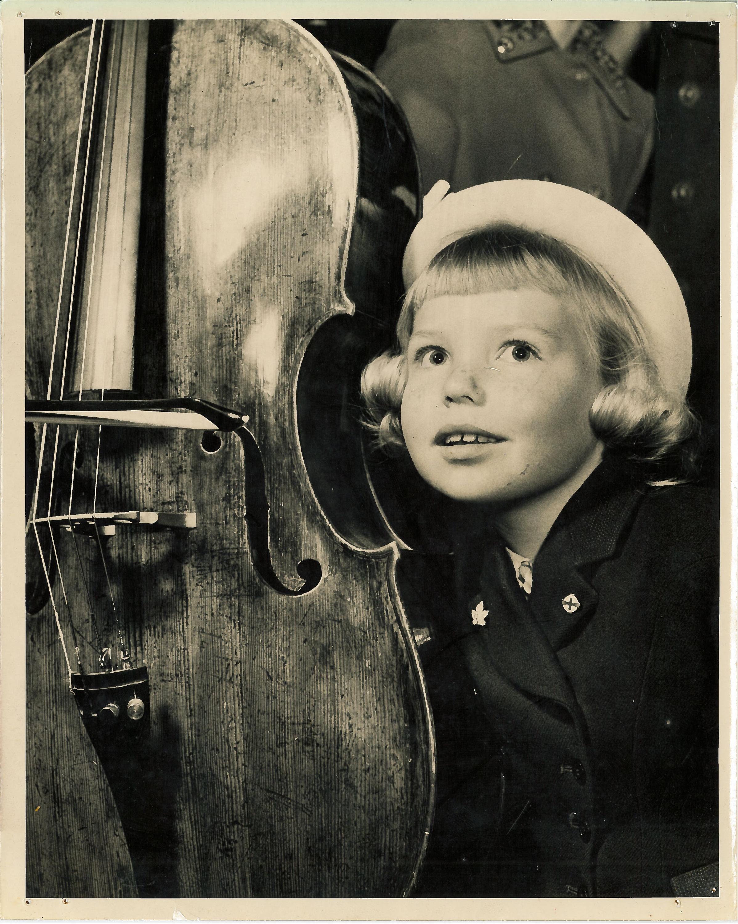 A young girl listens to a cello