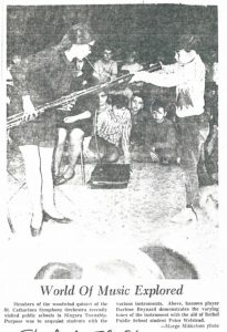 Un étudiant regarde un basson durant une démonstration. L’article du journal est « Toutes les possibilités de la musique sur terre. » 