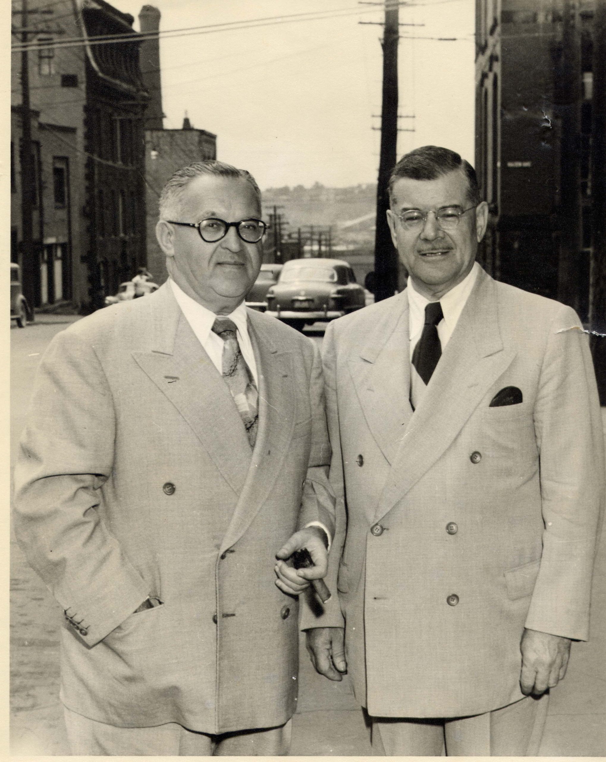 Two men in double-breasted business suits standing on sidewalk.
