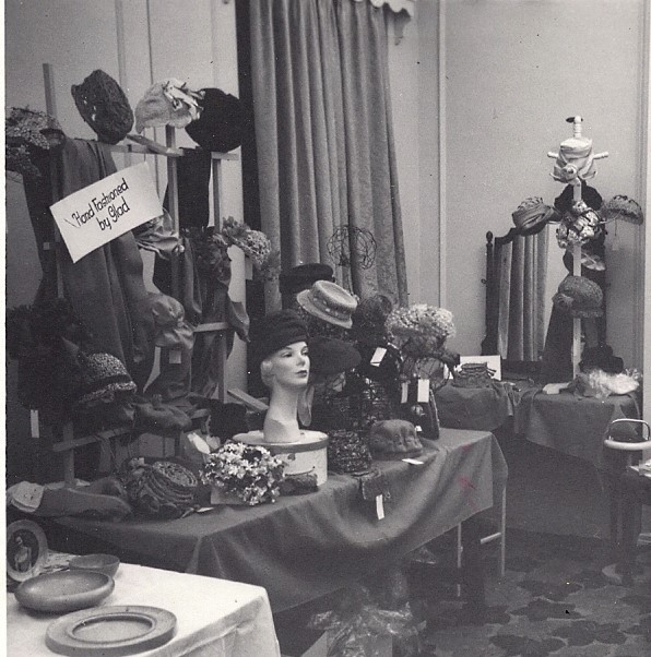 Display of women’s hats – some placed on mannequin heads, others on stands, all placed on tables.