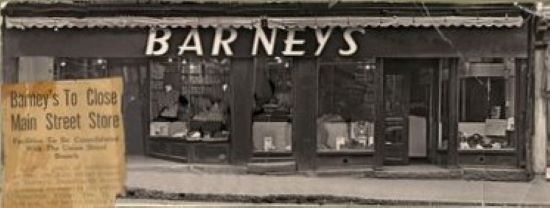 A storefront with large display windows and a doorway with a sign reading “Barneys”
