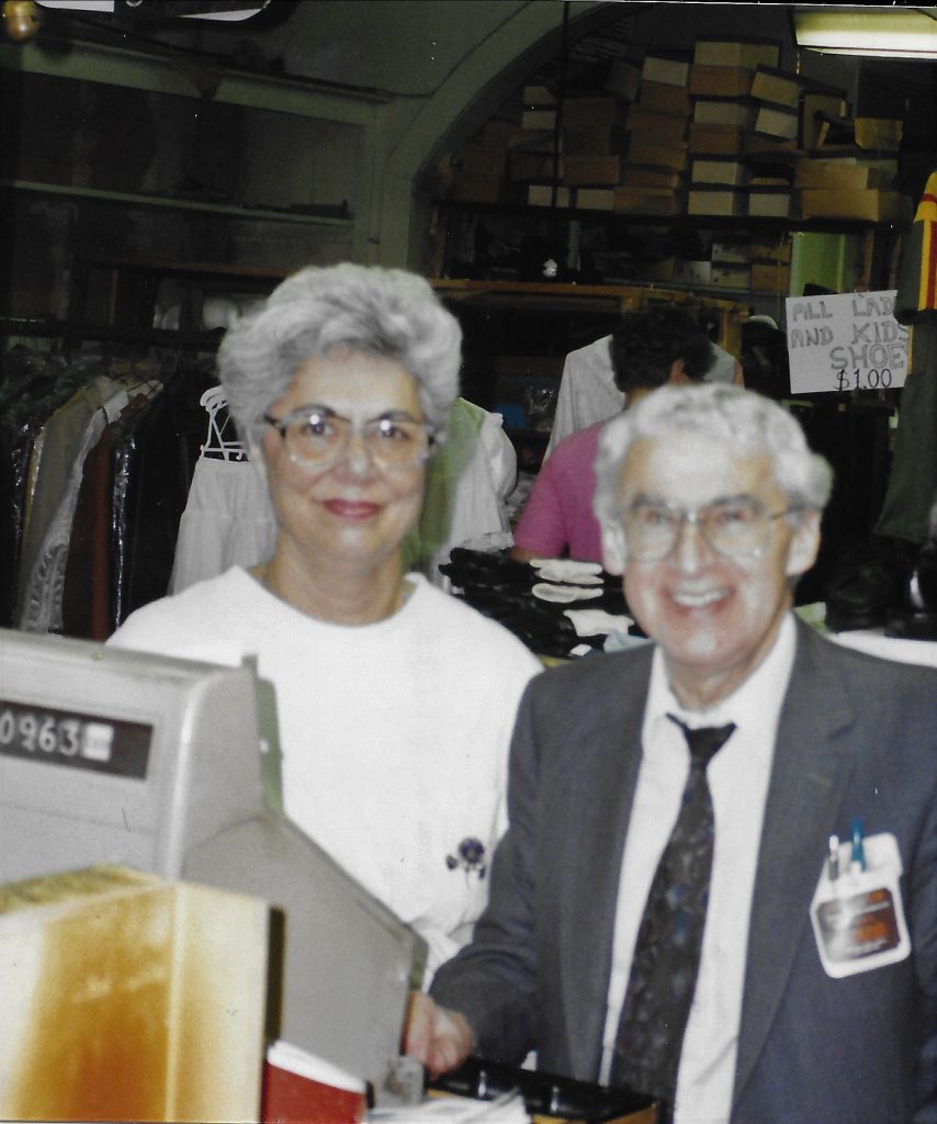 Man and woman standing behind cash resister in store.