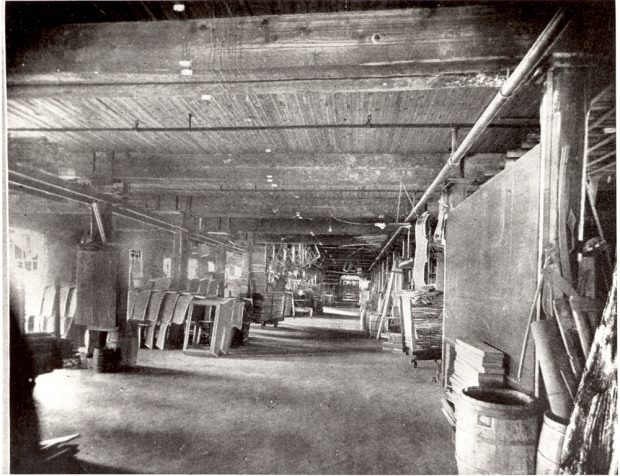 A factory room. Tools and wooden carriage bodies are piled along the walls.