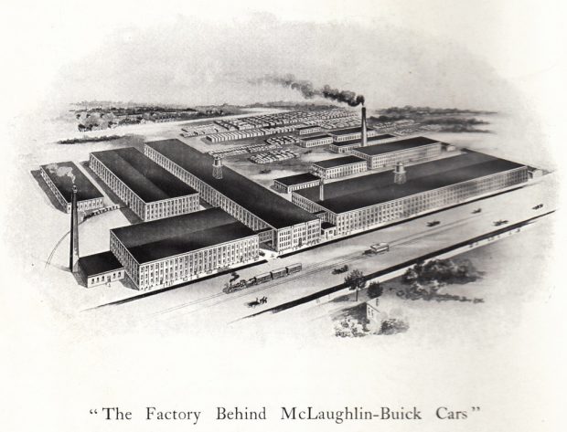 A black-and-white painting depicting 9 small and 4 large factory buildings. The buildings are placed next to two rail lines and a lot full of shipping containers. Two smokestacks are visible. The caption reads The Factory Behind McLaughlin-Buick Cars.