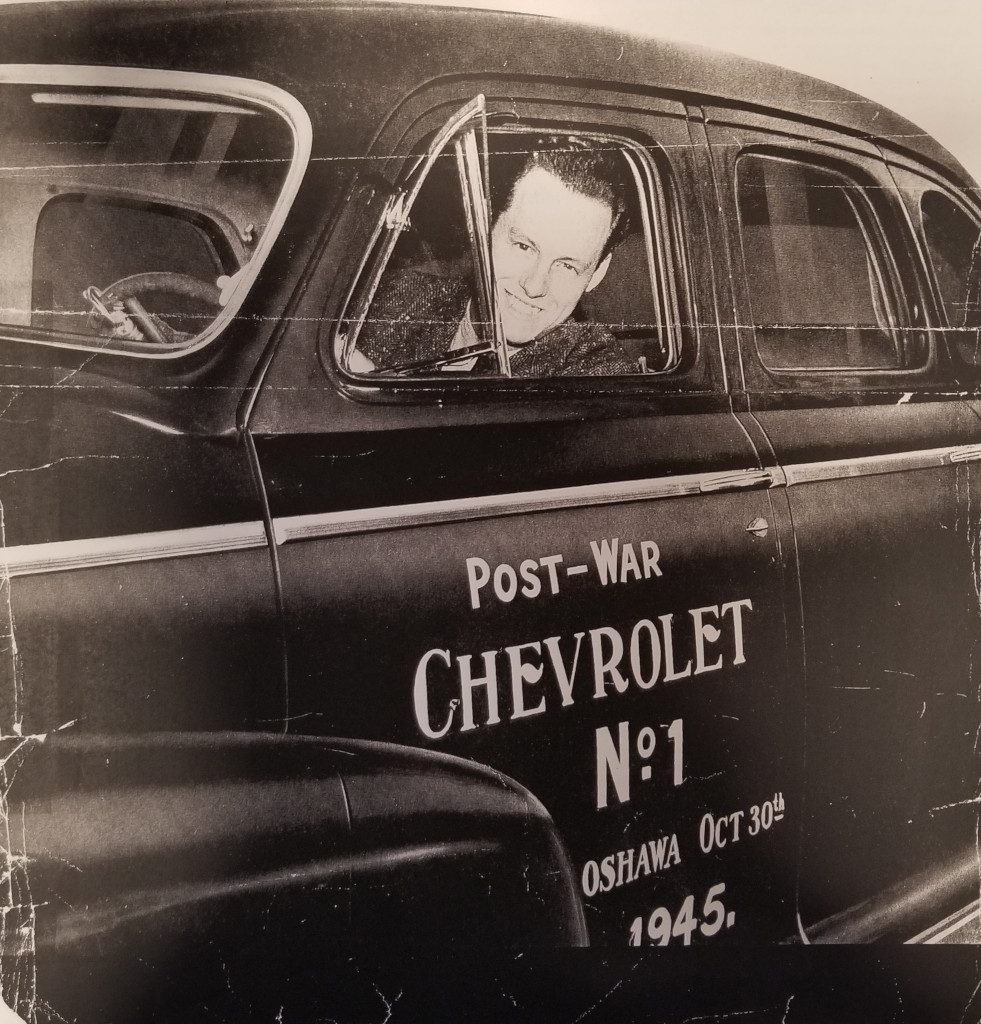 Photographie noir et blanc d’un homme au volant d’une voiture commémorative.