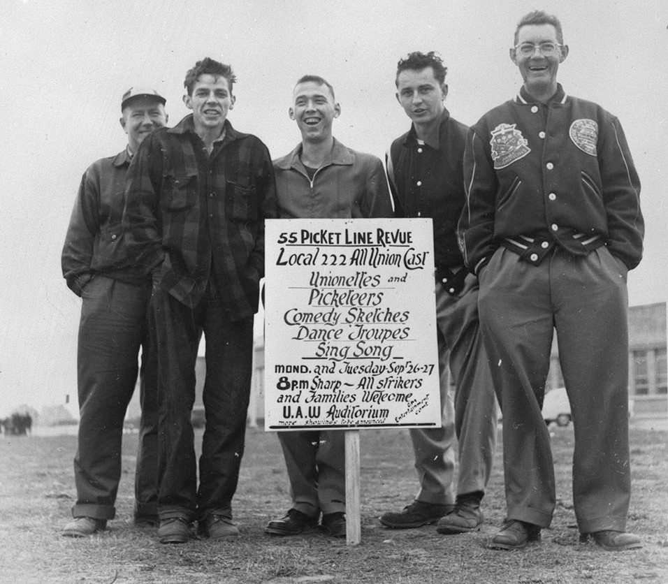 Black and white image of five men stand around a sign advertising 5 Picket Line Revue