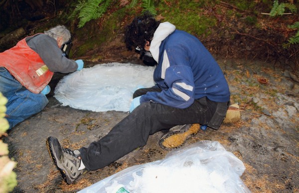 Graham Beard and Rob Bartlett sitting on the creek bed, applying fibreglass to the impression.