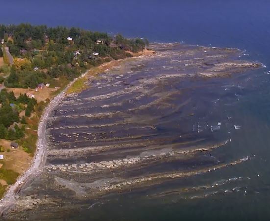 Aerial view of a coastline that has a series of rocky ridges extending into the sea