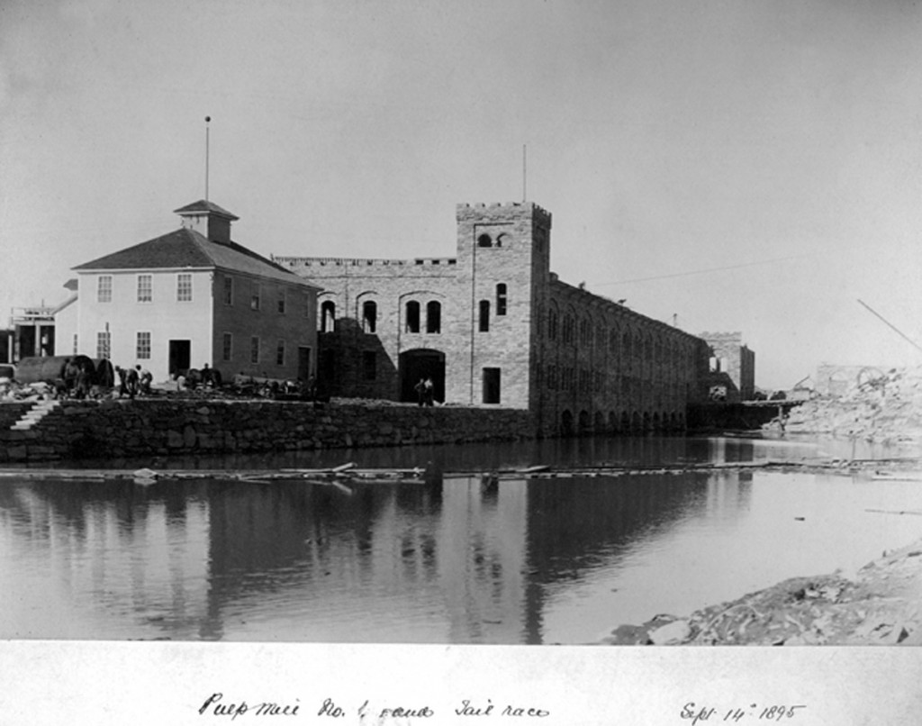 Image of the Pulp Mill No. 1 completed. The tall sandstone building is set back on the water.