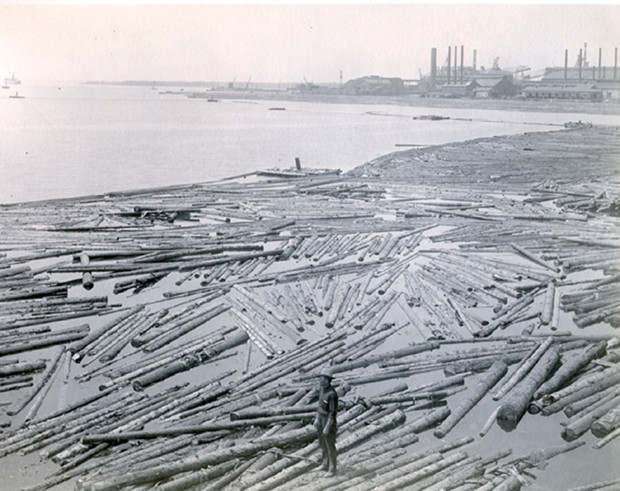Man standing on log boom in St. Mary's River