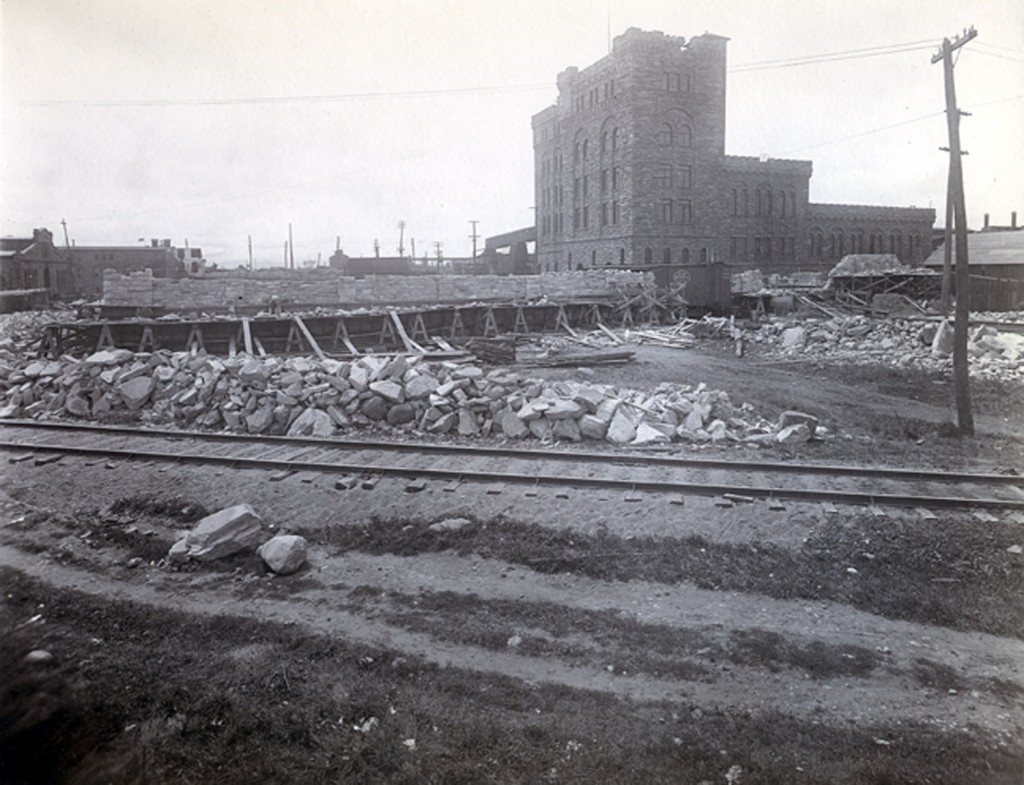 Rocks laying alongside of railway track, pulp tower in the background