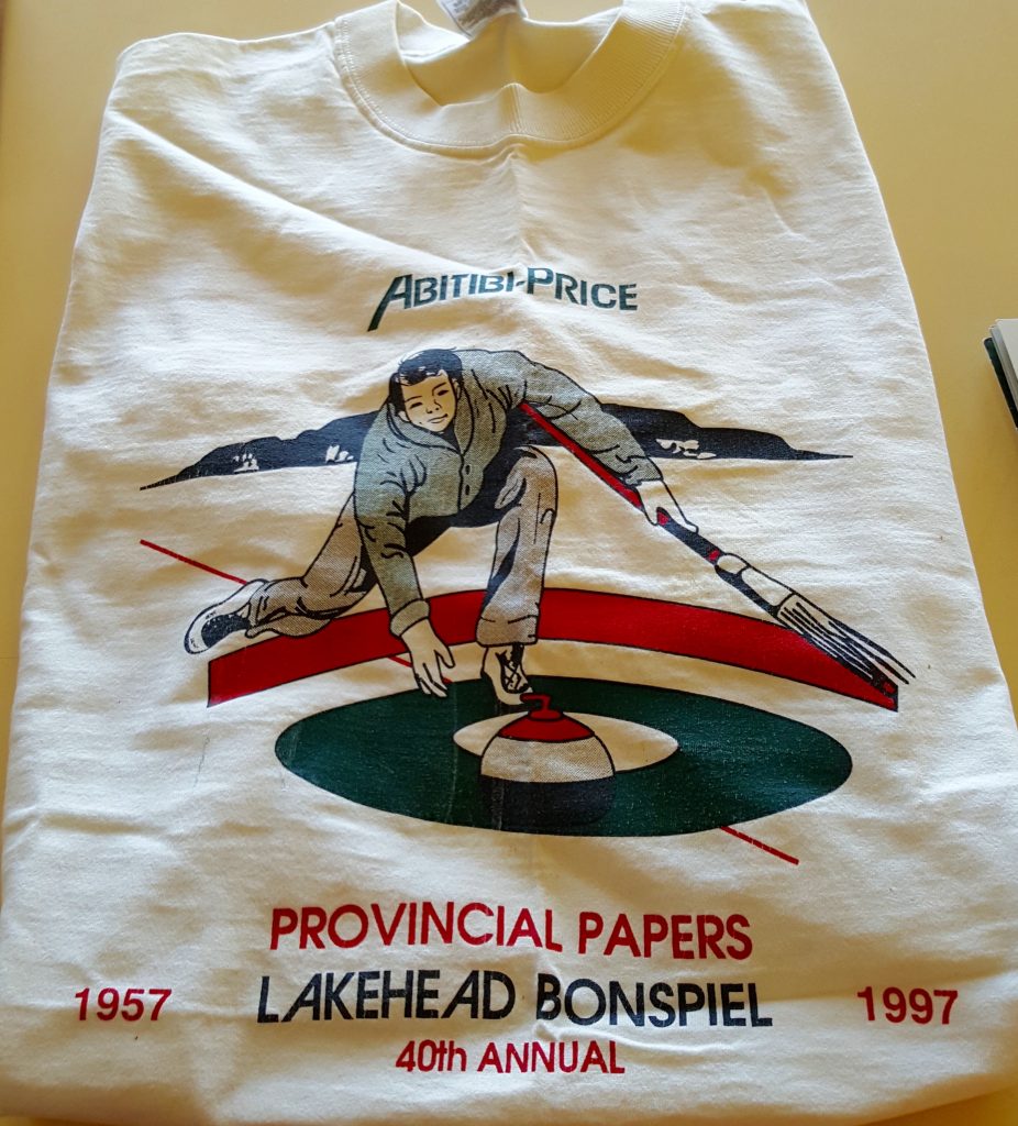 T-shirt blanc avec un joueur de curling. Inscription sur le t-shirt «Abitibi-Price Provincial Papers, Lakehead Bonspiel, 40th Annual, 1957-1997»
