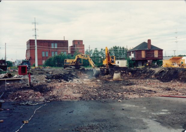 Cement in foreground, Clergue's block house is in the back right corner of the photo. Two excavators digging up ground in preparation for construction.