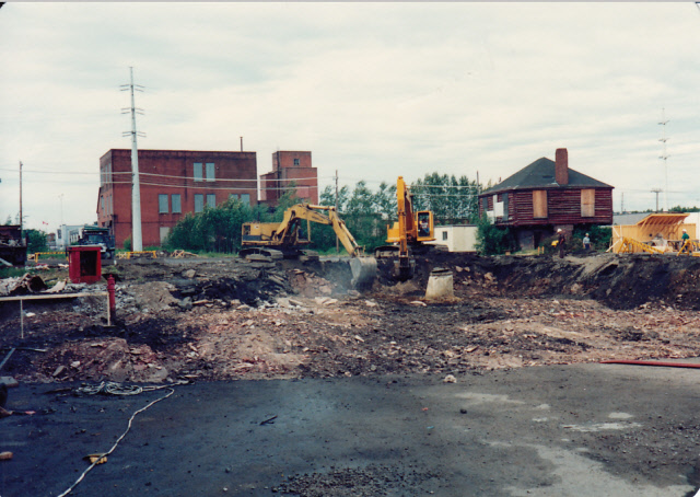 Cement in foreground, Clergue's block house is in the back right corner of the photo. Two excavators digging up ground in preparation for construction.