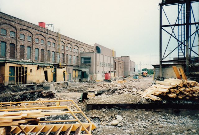 Construction site, Machine Shop to the left, gravel, and wood beams ready for construction in the foreground.