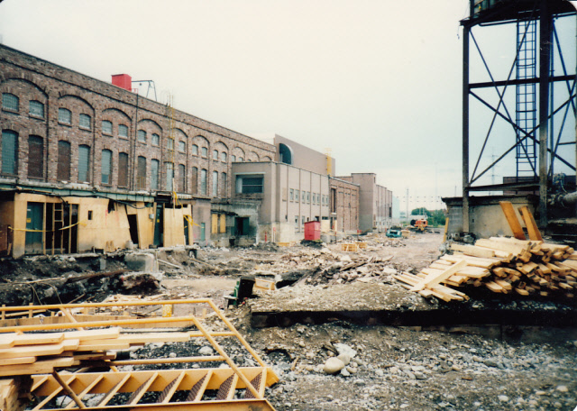 Construction site, Machine Shop to the left, gravel, and wood beams ready for construction in the foreground.