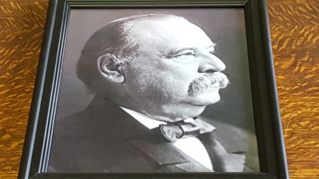 Black and white framed photograph of Francis Clergue. Frame and photograph were placed on a wooden table for this photograph.