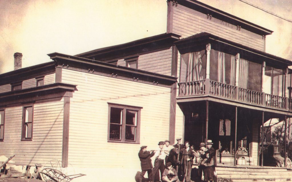 A group of hunters in front of a large house