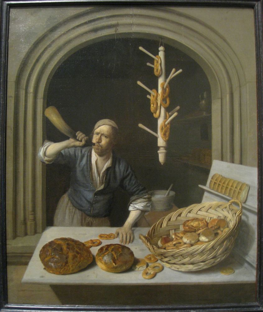 Framed oil painting: baker in his shop. Man with a cap blowing a horn. Light counter: round brown loaves, pretzels, wicker basket, pastries. Behind: pretzel display. Dark background. Warm, artisanal atmosphere.