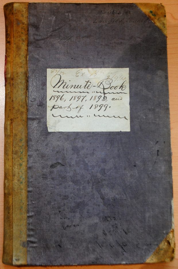 A colour photograph of the Langley Council’s Minute book for the years 1896 to 1899. The book has a blue cover with a yellowed spine and corners.