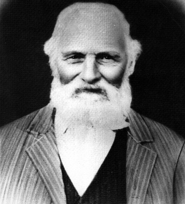 A black and white studio bust portrait of an elderly Philip Jackman with white hair and a beard. Jackman is wearing a striped suit, a dark vest, and a light coloured collared shirt.