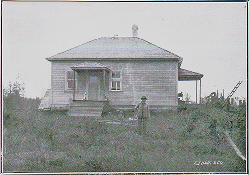 A black and white photograph of a man holding a cane standing in front of a house. The front of the house has five stairs that lead to the entrance of the house. There is a dog sitting in front of the door of the entrance.