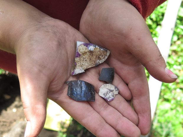 Two shards of ceramic and two fragments of glass in hands