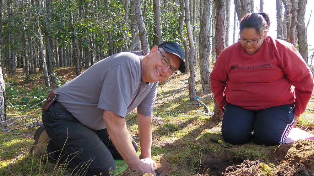 Two diggers around a survey in the woods