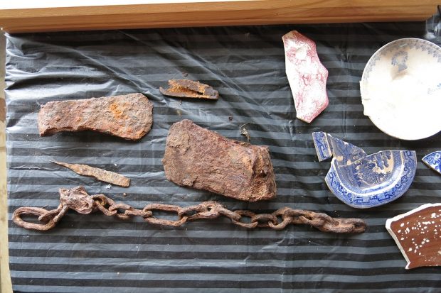 Various rusty objects and ceramic shards on a piece of fabric