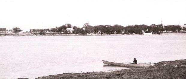 A man in a rowboat with houses in the background